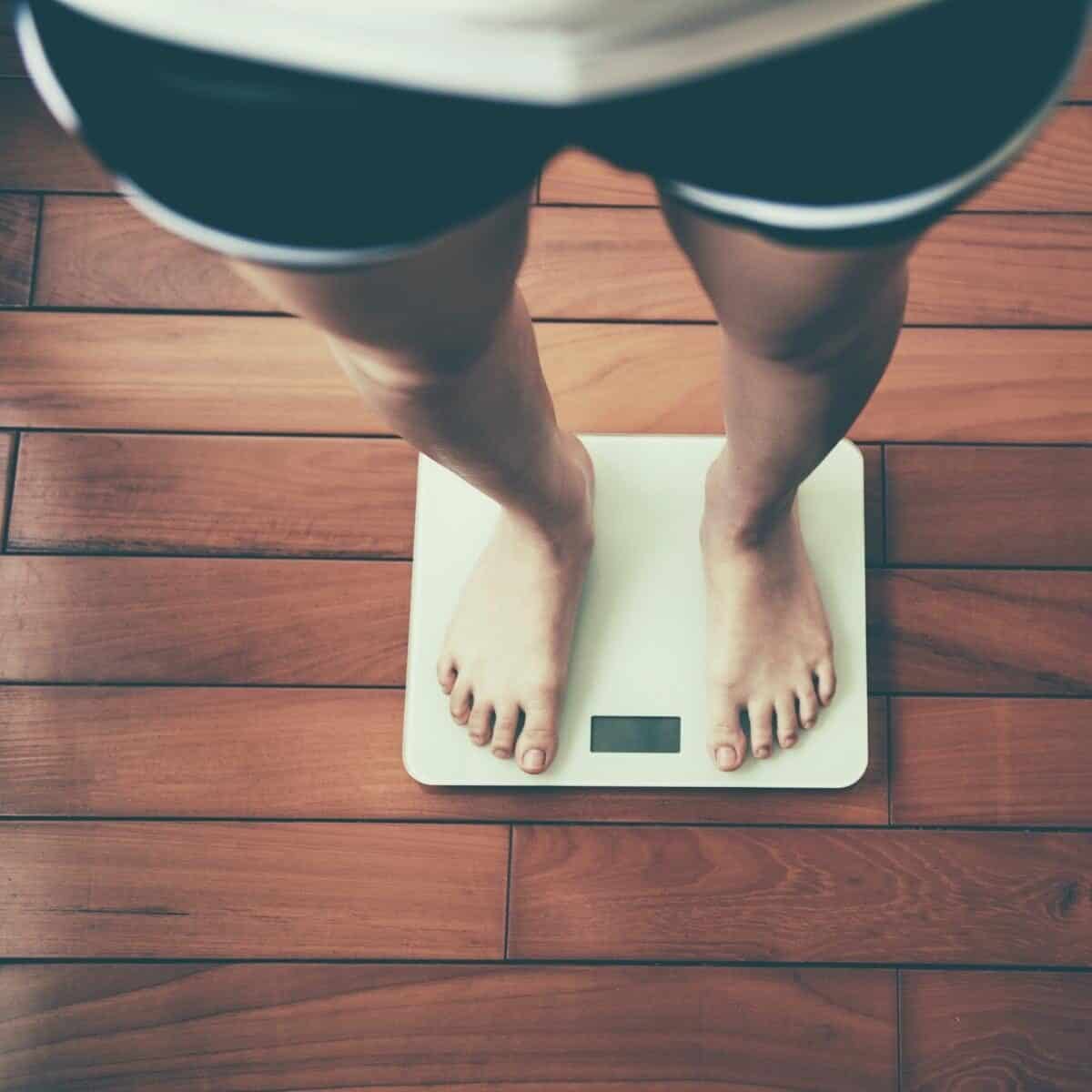 bathroom scales with a ladies legs standing on them.