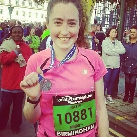 Katie, a smiling young lady wearing running clothes and wearing a medal from the Great Birmingham Run, a half marathon.