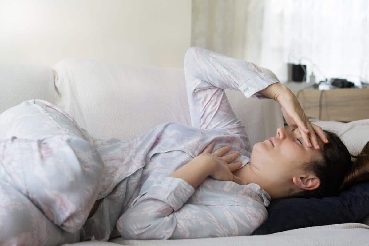 lady in bed in pain holding hand to her head