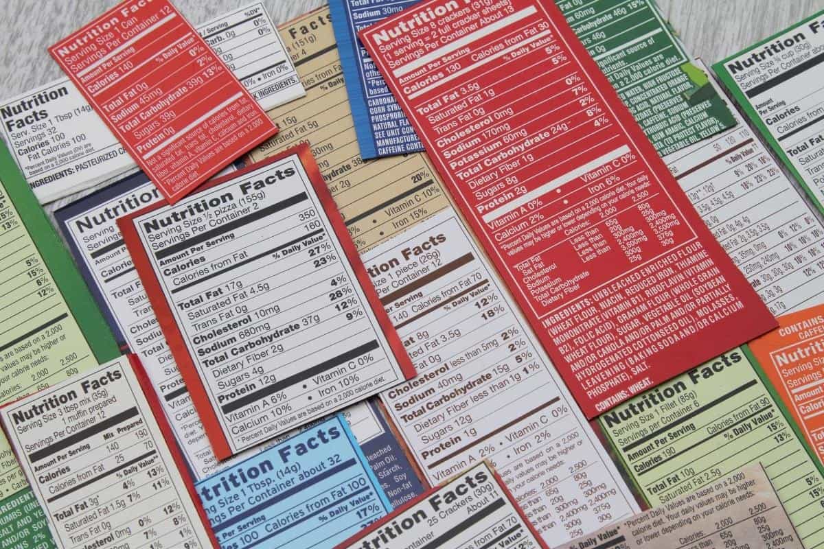 A collection of various nutrition facts labels from different processed food packages, displayed on a flat surface.