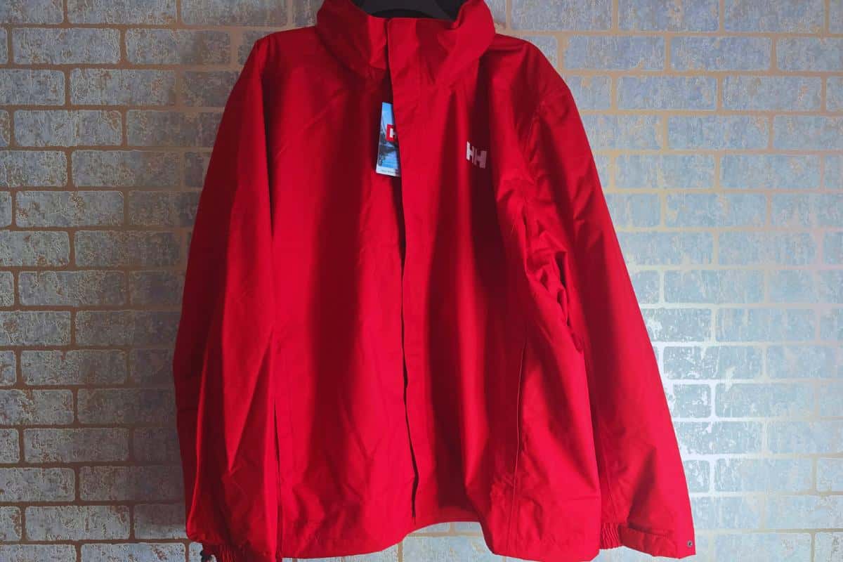 A red outdoor jacket, perfect for beginner hikers, hangs strikingly against a brick wall.