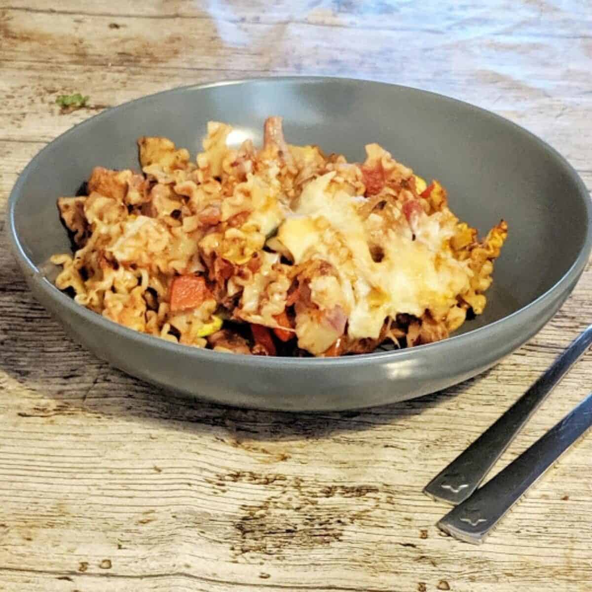 bowl of spicy sausage pasta bake topped with cheese