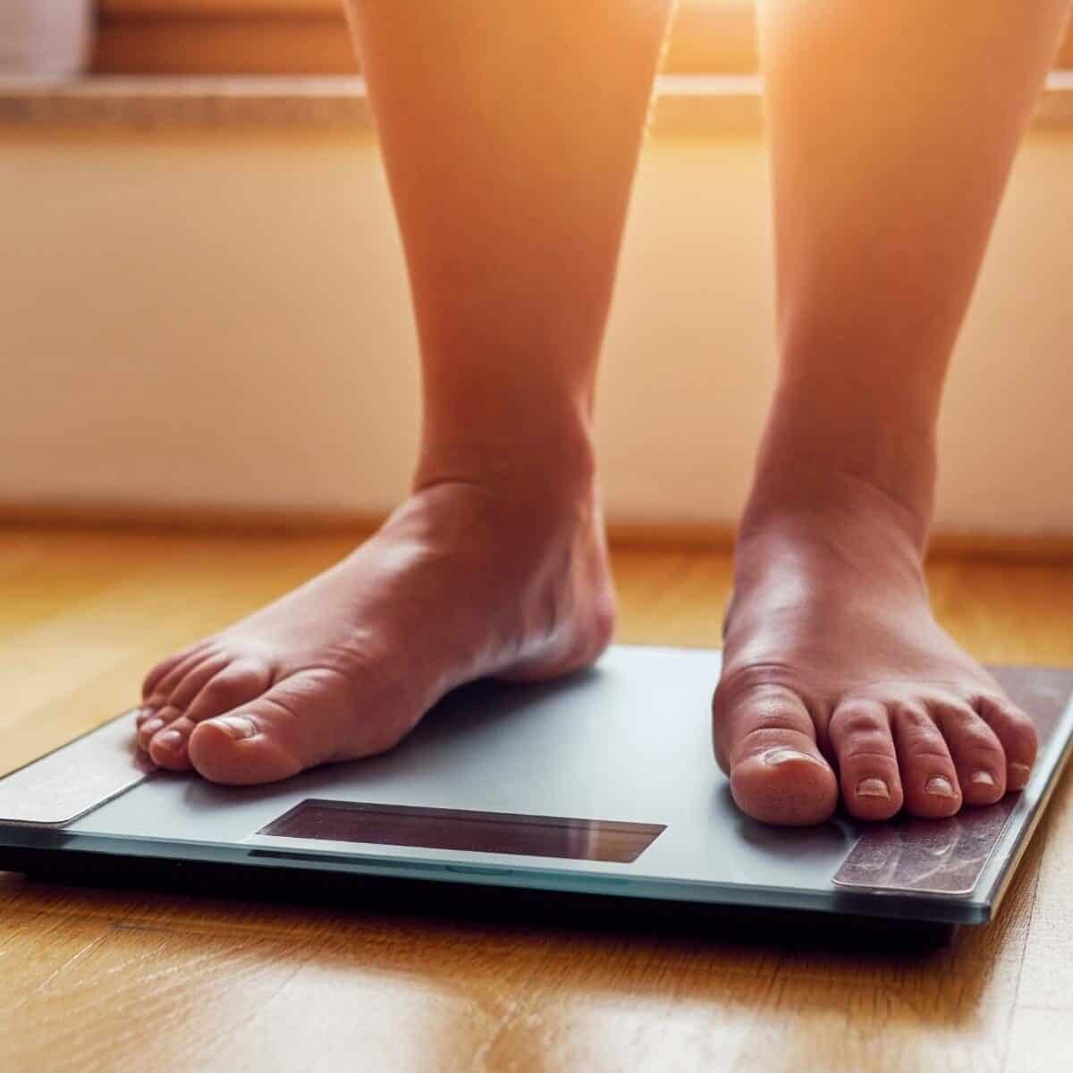 woman standing on bathroom scales on a wooden floor